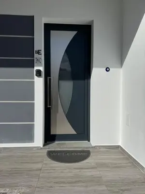 a black door on a white wall with a mat in front at E - Elegant Terraced Home with FREE Private Parking in Machico