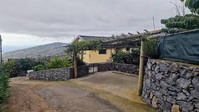 a house with a stone wall and a fence at Madeira Mountain Paradise - Casa da Levada do Arco in Arco da Calheta