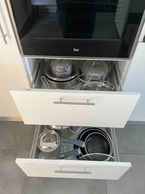 a white cabinet with a drawer with pots and pans at Moradia com piscina no Caniço in Caniço