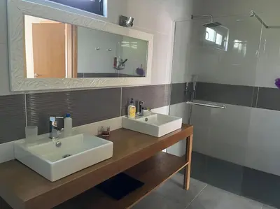 a bathroom with two sinks and a mirror and a shower at Moradia com piscina no Caniço in Caniço