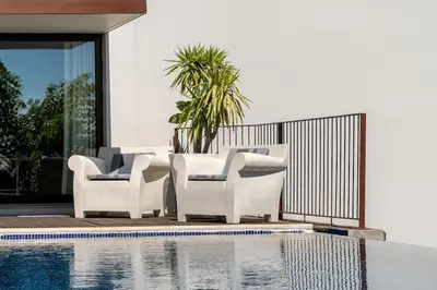 a pair of white chairs next to a swimming pool at Botanica Living Magnolia Apt in Quinta Grande