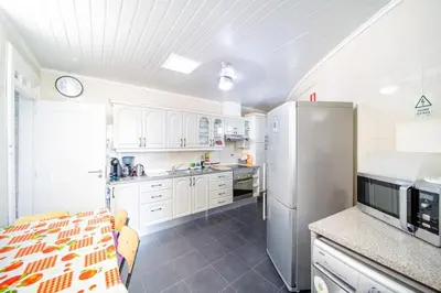 a kitchen with white cabinets and a stainless steel refrigerator at Villa bela vista 20th century house in Funchal