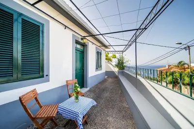 a table and chairs on a balcony with a view of the ocean at Villa bela vista 20th century house in Funchal