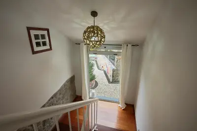 a hallway with a staircase with a window and a chandelier at Casas Maravilha - Casa Grande by Homie in Calheta