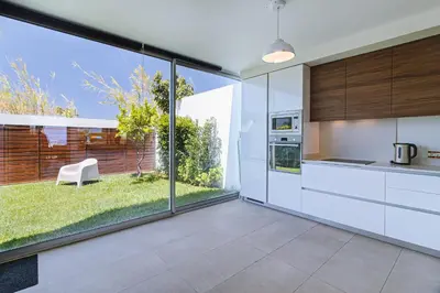 a kitchen with white cabinets and a large window at Villa Blue Sagres D in Sagres