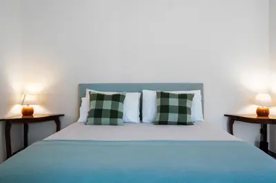 a bed with green and white pillows and two lamps at Forum T0 Plus in Funchal