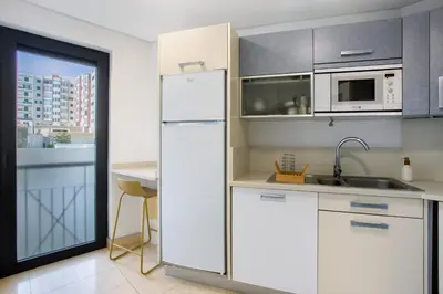 a kitchen with white cabinets and a white refrigerator at Forum T0 Plus in Funchal