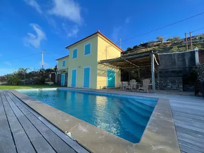 a house with a swimming pool in front of a house at Villa Pargo in Fajã da Ovelha
