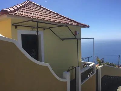 a house with a door and a balcony at Villa Pargo in Fajã da Ovelha