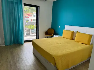 a bedroom with a bed with yellow pillows and a window at B - BEAUTIFUL 2 Bedroom Modern Townhouse with Private Parking in Machico