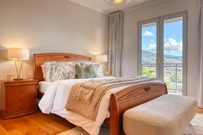 a bedroom with a bed and a large window at Funchal Atrium, a Home in Madeira in Funchal