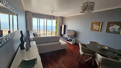 a living room with a couch and a tv and a table at Seaview Relax Apartment in Caniço