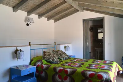a bedroom with a bed with a green comforter at Barranco do Zambujeiro in Vila do Bispo
