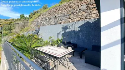 a balcony with a table and a stone wall at Espirito do Mar - Premium Villa with Jacuzzi in Estreito da Calheta