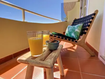 a balcony with two chairs and two glasses of orange juice at Portinho's View by LovelyStay in Caniço