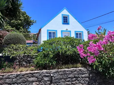 a white house with flowers in front of a stone wall at Lucky Lemons Boutique Houses Madeira 1 in Calheta