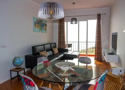 a living room with a black couch and a glass table at Apartamento Bartolomeu By Horizon View Madeira in Caniço