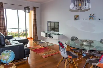a living room with a glass table and chairs at Apartamento Bartolomeu By Horizon View Madeira in Caniço