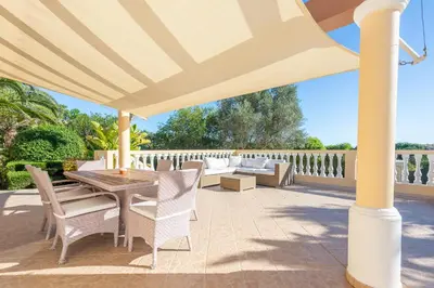 a patio with a table and chairs under a umbrella at Lote 50 at Boavista Resort Lagos in Lagos