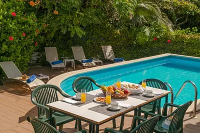 a table with a bowl of fruit next to a swimming pool at Villa Amelia in Caniço
