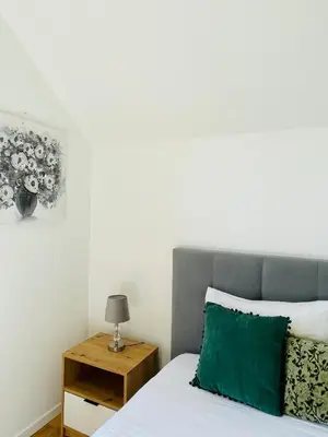 a bed with a green pillow and a side table at Cozy House in Funchal