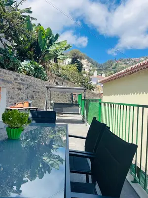 a glass table with two chairs on a balcony at Cozy House in Funchal