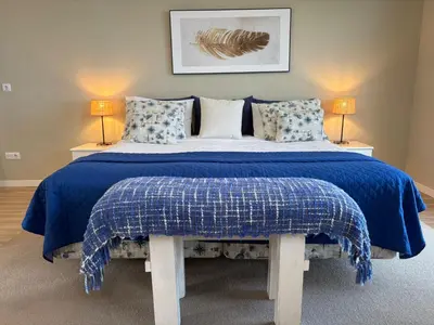 a bedroom with a bed with a blue blanket and two lamps at Villa Alta Vista in São Jorge