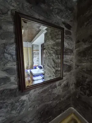 a mirror on a stone wall in a room at Casa Rosa in Camacha