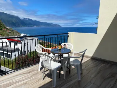 a table and chairs on a balcony with a view of the ocean at The Vista House in Ponta Delgada