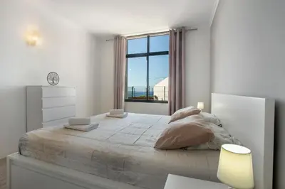 a white bedroom with a large bed with a window at Refúgio Na Cidade 104 in Funchal