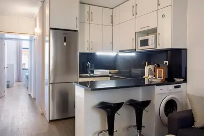 a kitchen with white cabinets and black counter tops at Refúgio Na Cidade 104 in Funchal