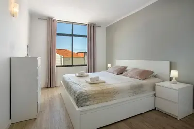 a white bedroom with a white bed and a large window at Refúgio Na Cidade 104 in Funchal