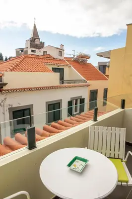 a table and chairs on a balcony with a building at ISABELLA STUDIOS FUNCHAL in Funchal