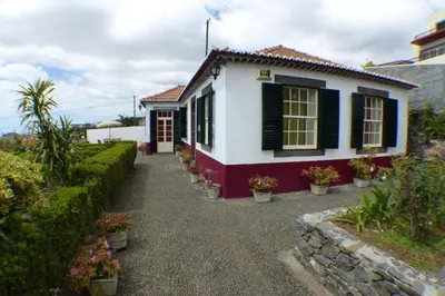 a white house with black shuttered windows and plants at Casa da Avó Benvinda in Funchal