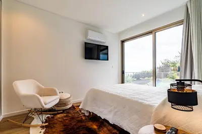 a bedroom with a large bed with a bench on it at One Sweet World in Calheta
