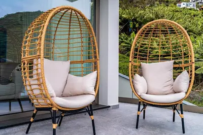 two wicker chairs with pillows sitting on a porch at One Sweet World in Calheta