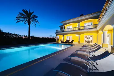 a house with a swimming pool with chairs around it at Casa Ferrel - Luxury 9 Bedroom Villa with Indoor & Outdoor Pools in Lagos