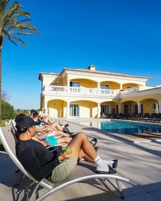 a group of people sitting in lawn chairs by a pool at Casa Ferrel - Luxury 9 Bedroom Villa with Indoor & Outdoor Pools in Lagos