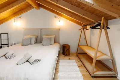 a bedroom with a large white bed in a attic at Casa elegante em Vila tranquila in Barão de São Miguel