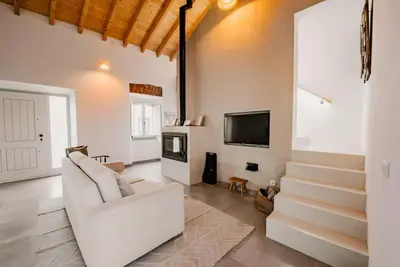 a living room with a white couch and a tv at Casa elegante em Vila tranquila in Barão de São Miguel