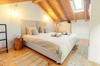 a large white bed in a room with a wooden ceiling at Casa elegante em Vila tranquila in Barão de São Miguel
