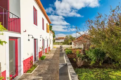 a path between two white buildings with red windows at Casa os Gauleses in Gaula