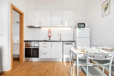 a kitchen with white appliances and a table with chairs at Casa os Gauleses in Gaula