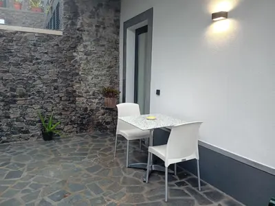 a table and chairs in a room with a stone wall at Vista Funchal Ⅰ in Funchal