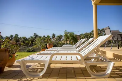 a row of white lounge chairs on a patio at D05 - Amadeus Sunset Villa in Mato Porcas