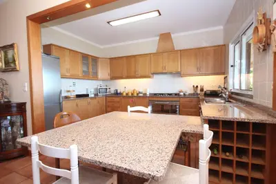 a kitchen with wooden cabinets and a table with chairs at Quinta do Santo by LovelyStay in Santo da Serra