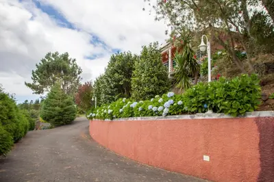 a brick retaining wall with flowers on a road at Quinta do Santo by LovelyStay in Santo da Serra