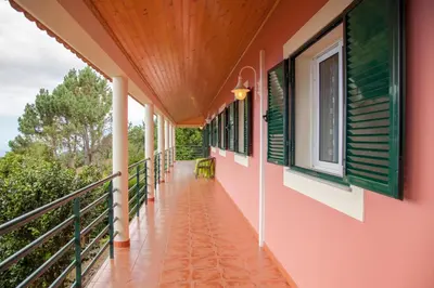 a balcony of a house with pink walls and green windows at Quinta do Santo by LovelyStay in Santo da Serra
