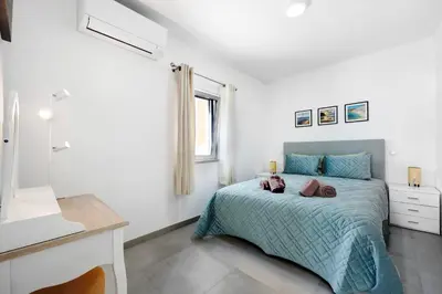 a white bedroom with a bed and a window at Casinha in Burgau