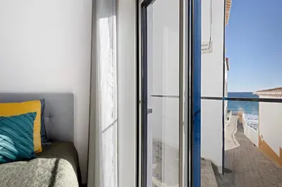 a bedroom with a window with a view of the ocean at Casinha in Burgau